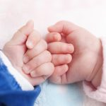 Twin babies bumping knuckles.